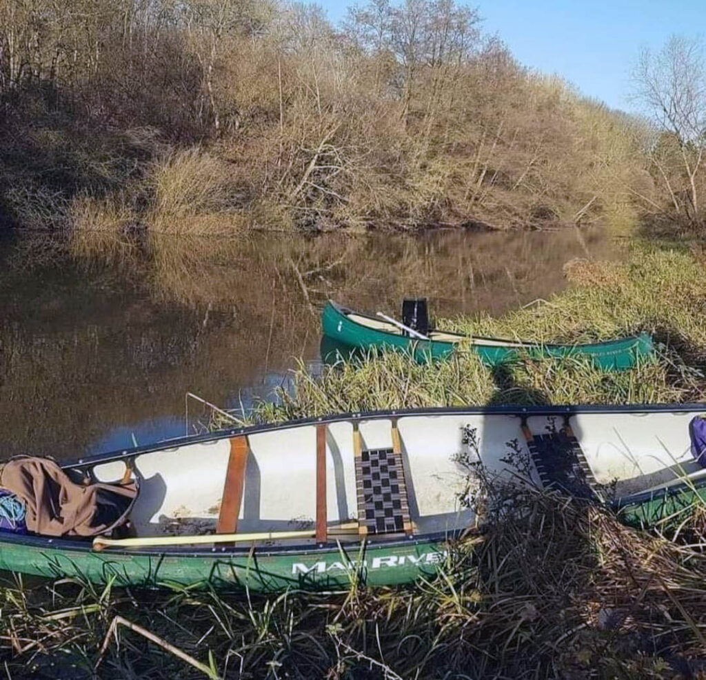 Canoeing Experience - 2 Canoes on a River Bank.